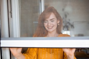 A pretty woman safeguarding her house from bugs by closing the net window