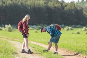 man and woman spraying with tick repellent while hiking in Infected forest to prevent summer insect bites